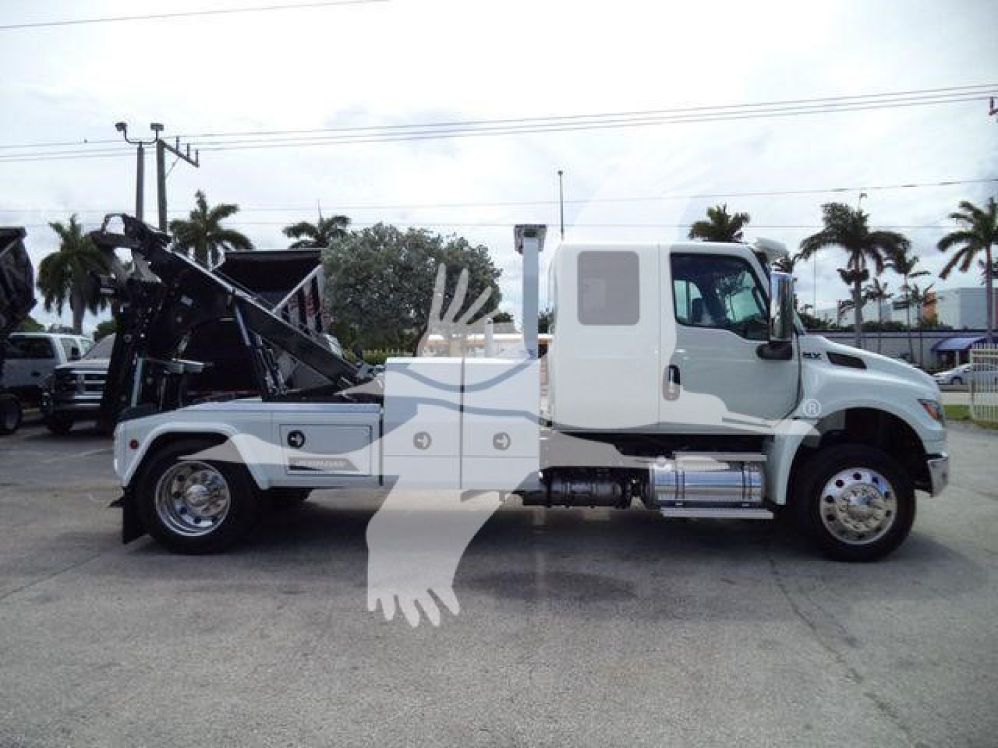 White International MV truck side view with a mounted winch and hydraulic arm. Visible text includes stock number J86683FM and category indicators for winch, truck type, and new/used status.