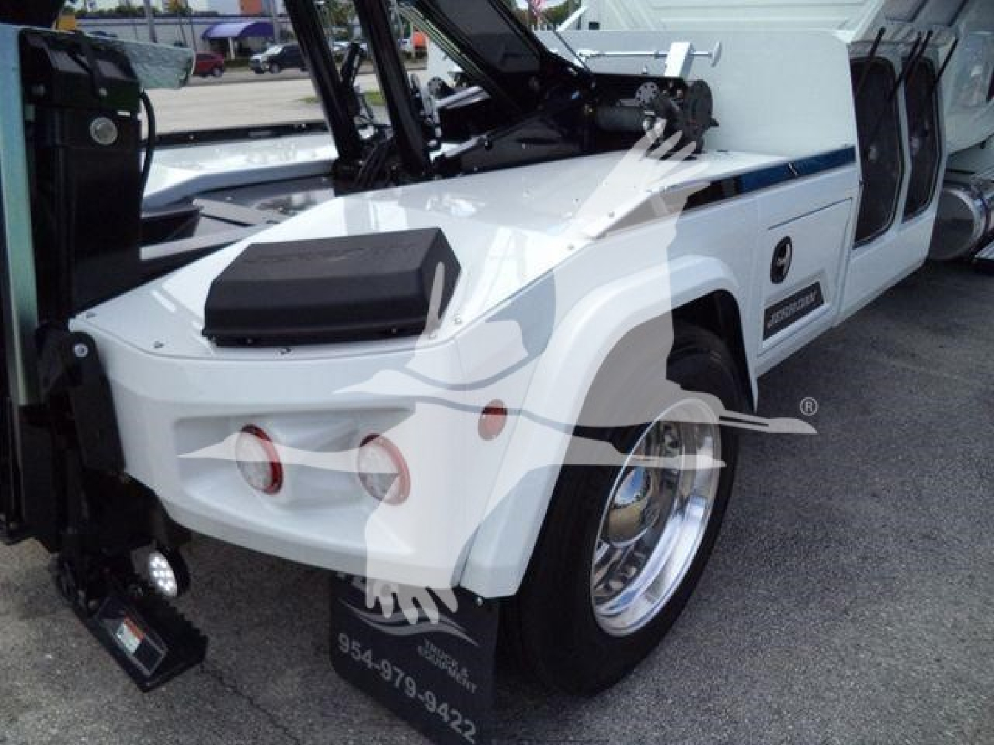 Winch-equipped white International MV truck front-left view showing hydraulic winch assembly and bold fenders.