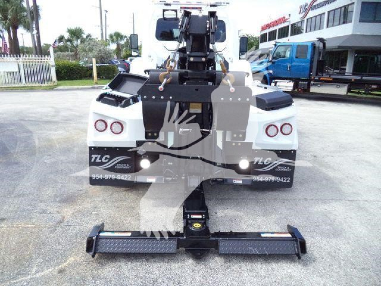 International MV tow truck rear with integrated winch and heavy-duty hitch showing dual taillights and rear bumper; winch cable and hook assembly visible.