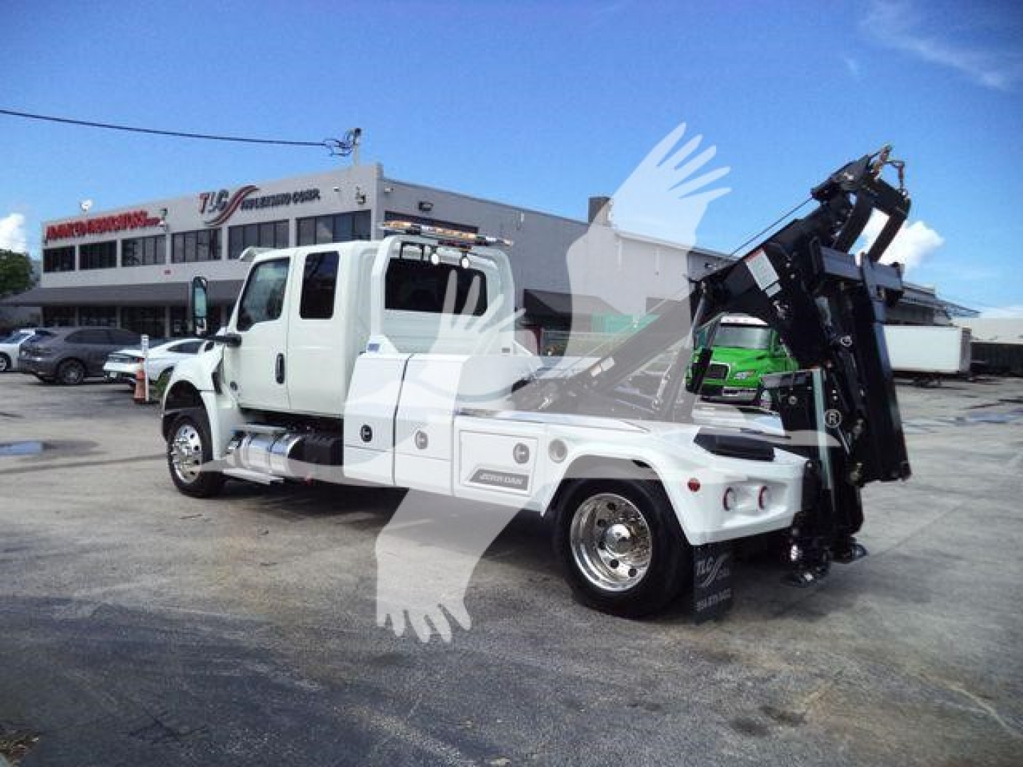 16-volt white International MV heavy-duty truck with a mounted winch and crane attachment at the rear, front cab, and side steps visible.
