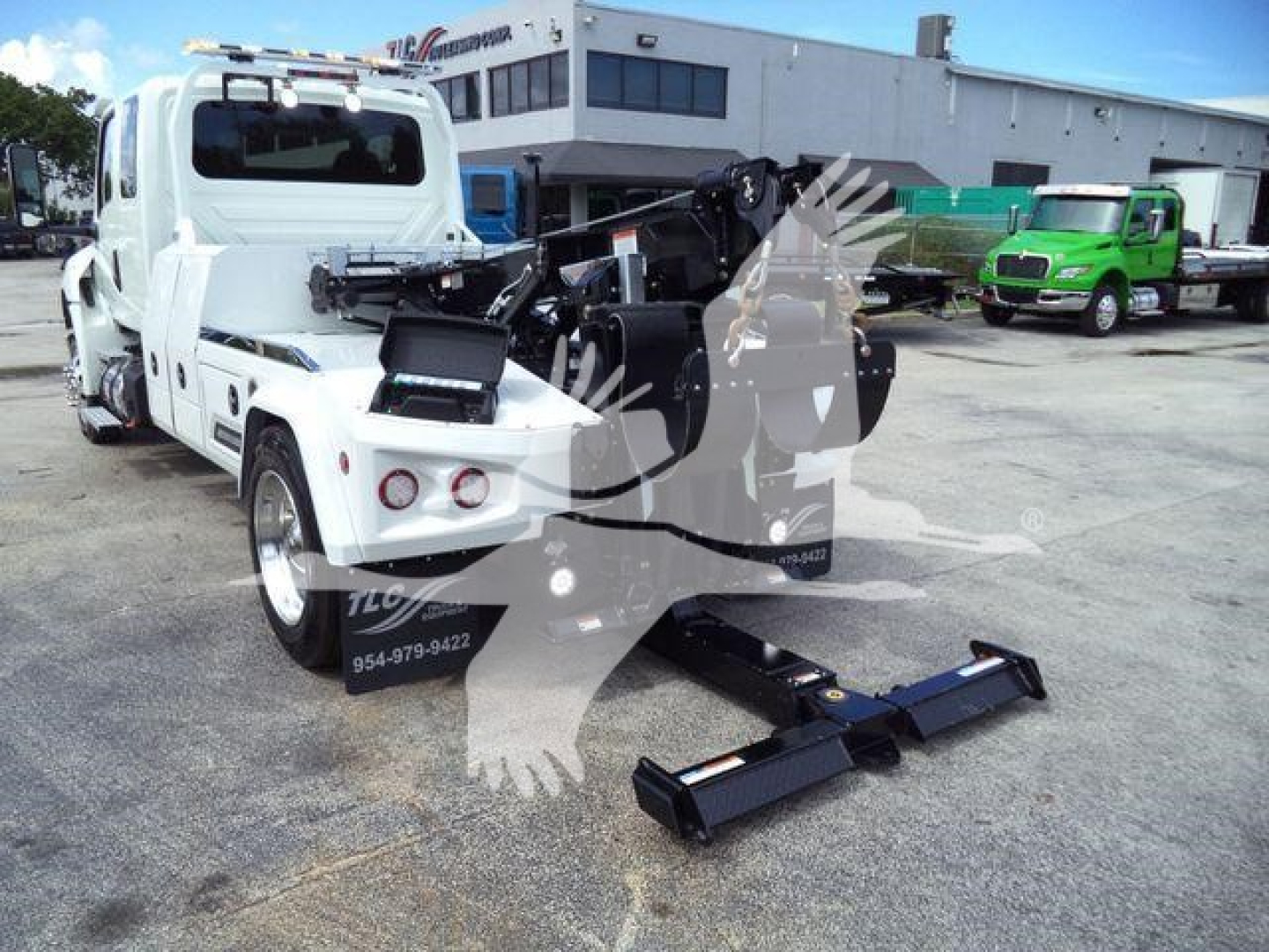 Truck rear view with hydraulic winch and heavy-duty hitch, white International MV truck in a dealership lot.