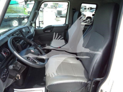 Truck cab interior view showing steering wheel, driver seat, and dashboard in a 2025 International MV from the left side.
