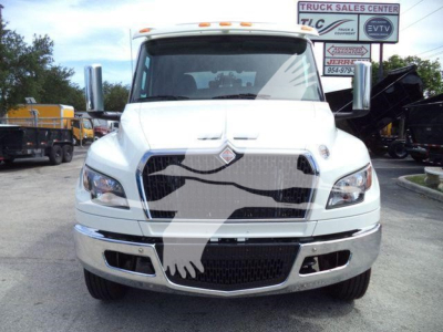 Front view of a white 2025 International MV truck with large grille and winch category sign in background.