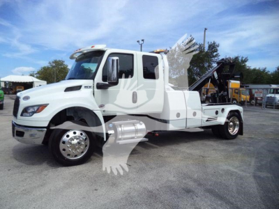 International MV truck with winch equipment on a white cab chassis, side profile view showing dual rear axles and winch/inclined bed.