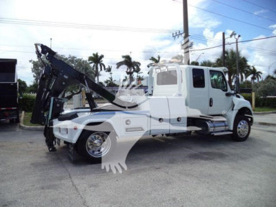 International MV winch truck with white cab and twin rear axles showing crane-winch assembly and side steps.