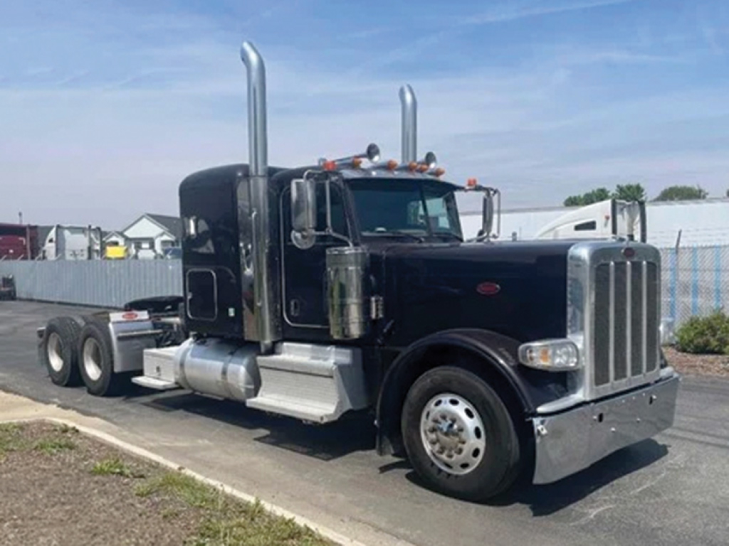 Peterbilt 389 extended hood truck in black, side view showing tall intake stacks and chrome fuel tanks, front grille and bumper, 6x4 tractor configuration.