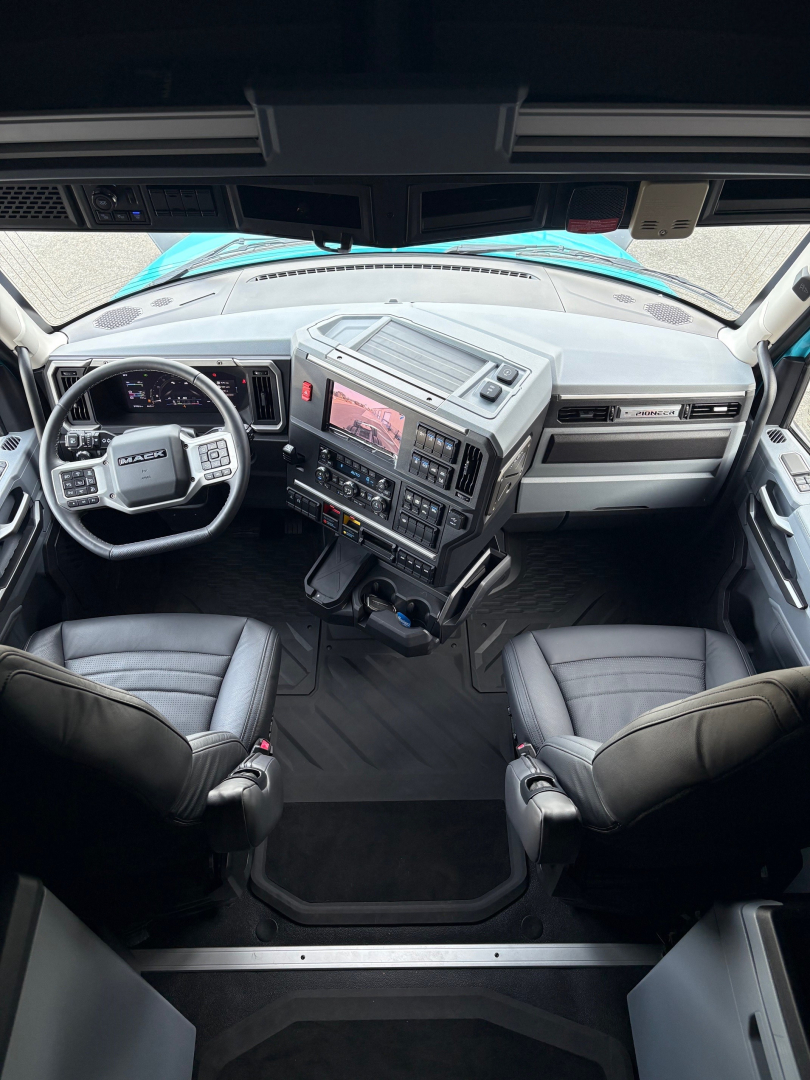 Truck cab interior showing steering wheel, dashboard, and center console with digital display in Mack PR64T76H truck.