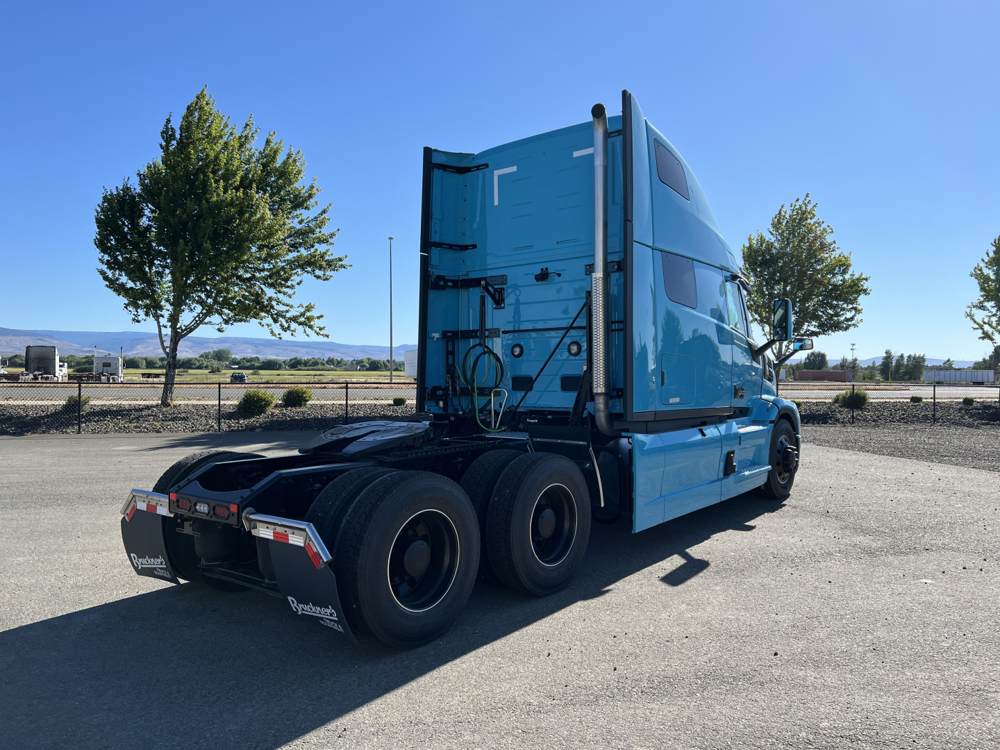 Mack PR64T76H conventional sleeper tractor viewed from rear-left side showing blue cab, rear wheels, and fifth wheel area.