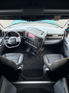 Truck cab interior showing steering wheel, dashboard, and center console with digital display in Mack PR64T76H truck.