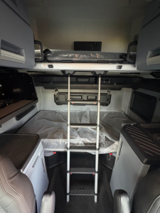 Mack PR64T76H sleeper cab interior with bunk bed area, ladder, storage compartments, and metallic ladder in center.