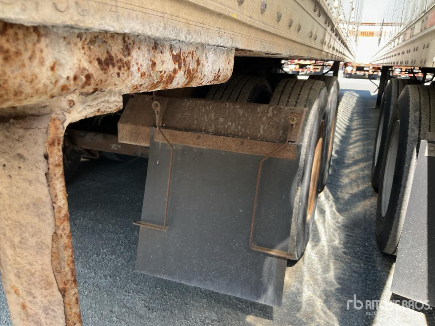 Trailer underside showing rusted frame and dual rear wheels with mud flaps under a Wabash trailer.
