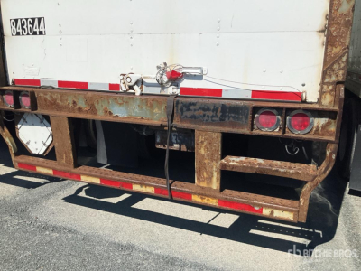 Rear of a trailer showing rusted metal frame and bumper with red circular taillights and a white panel container.