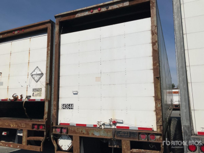 Trailer door and frame showing white panel with rusted perimeter; rear of a box trailer with light red and white reflective tape along lower edge; small identification plate near left side.