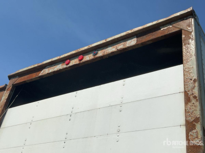 Trailer rear opening showing rusted frame and white segment panels with riveted joints.