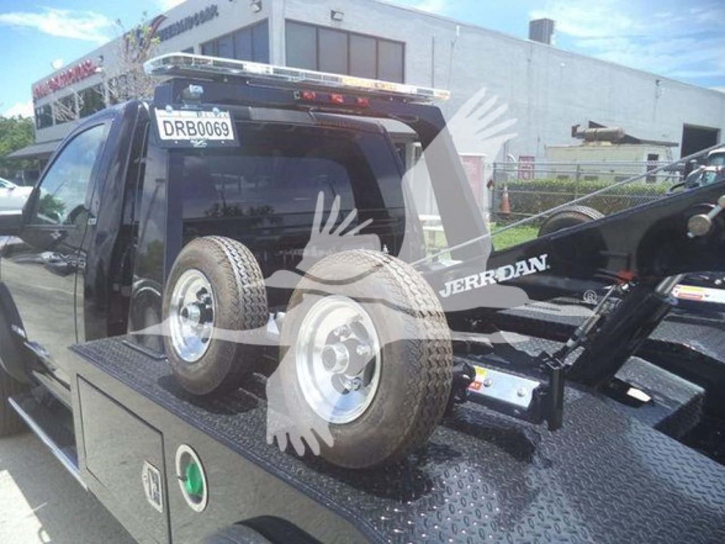 Ram 5500 SLT service body with winch equipment on rear bed, two spare tires mounted, and vehicle rear window visible.