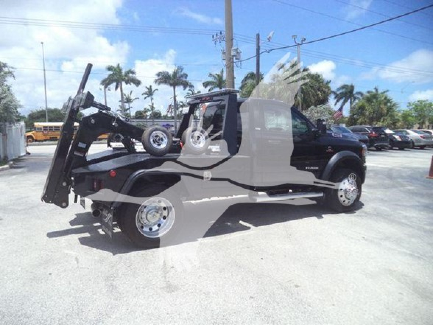 Ram 5500 SLT truck with mounted winch and crane in folded position, side view showing dual rear wheels and extended cab, dealership lot in background.