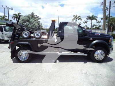 Ram 5500 SLT tow truck side view showing spare wheel, tow hoist, and winch undercarriage with black body and chrome wheels.