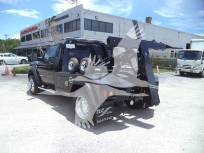 Ram 5500 SLT tow truck with a large rear loader/winch system in the bed, side view showing wheel, rear fender, and winch assembly
