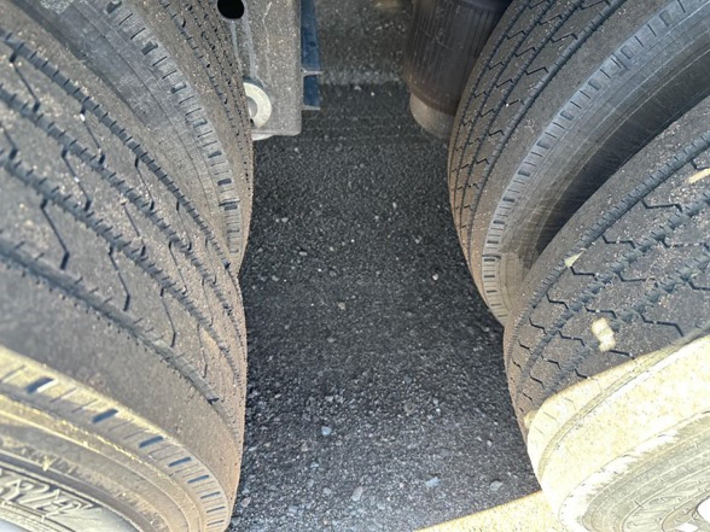 Dual rear axles of a trailer showing tandem tires and underside of a closed deck trailer.