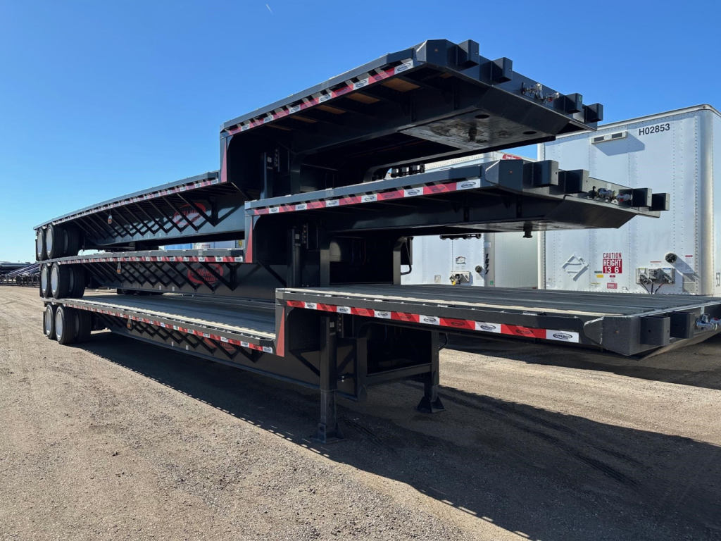 2026 Dura Haul closed tandem drop deck trailer stacked on flatbed with multiple levels, showing black steel structure, red/white safety stripes, and underside supports.