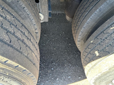 Truck trailer tandem drive tires and gap between axles showing tread details and road grime on the surface.