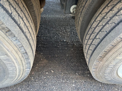 Two trailer axles with dual tires on a Dura Haul steel closed tandem drop deck trailer showing tread detail.