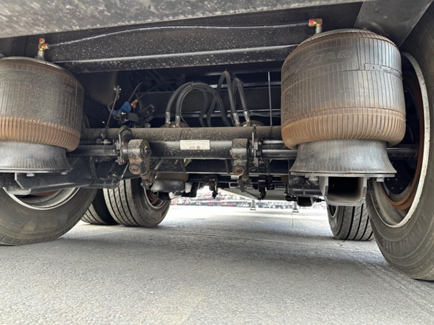 Trailer underside showing air springs, suspension axle, and driveshaft components with dual rear wheels.