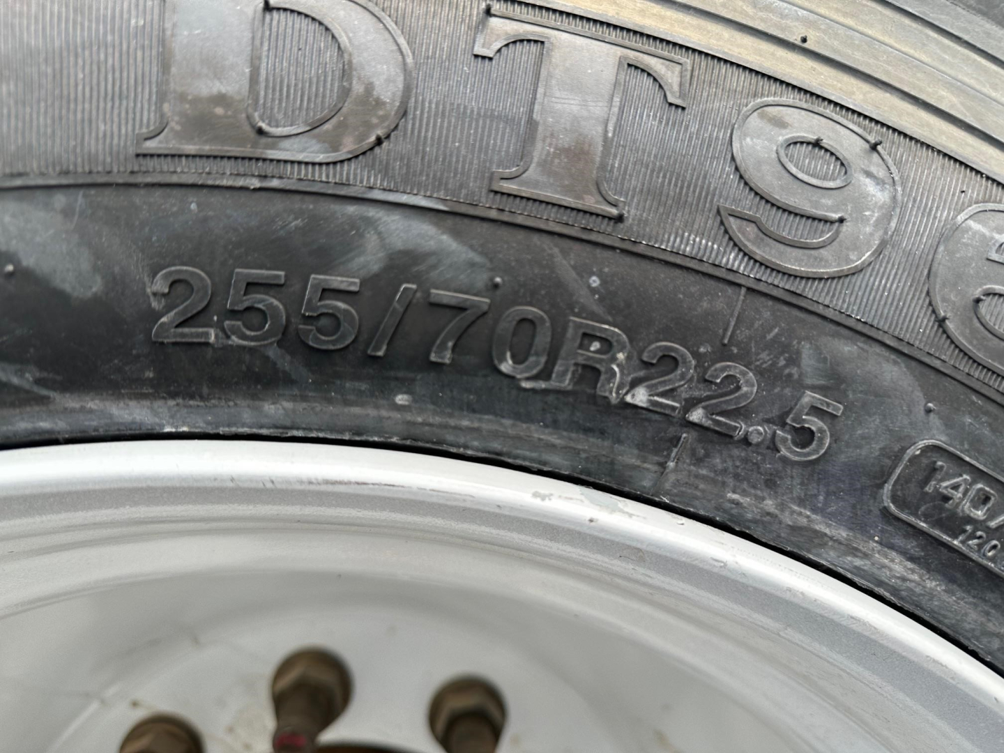Trailer tire sidewall showing 255/70R22.5 text and wheel rim.