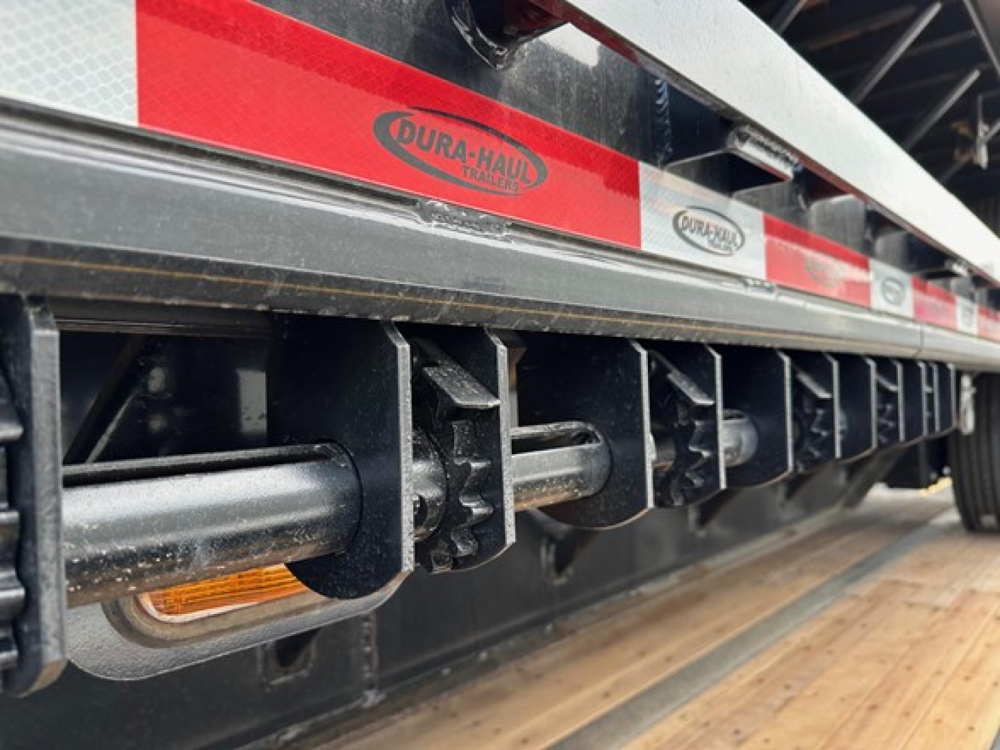 Dura-Haul closed tandem steel drop deck trailer undercarriage with side reflectors and logo panels visible.