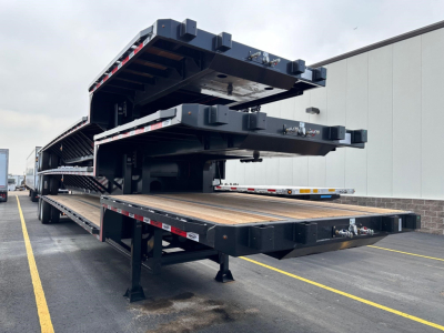 Drop deck trailer stacked with multiple flatbed sections showing aluminum deck surface and black framing.