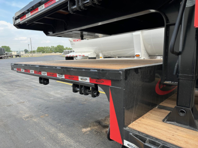 Trailer flatbed deck extending from a drop deck trailer with wooden planks and black steel frame, undercarriage visible with red and white reflective tape