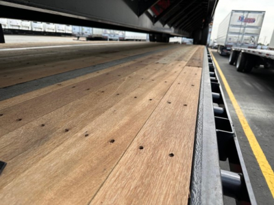 Drop deck trailer bed showing wooden planks and black steel frame.