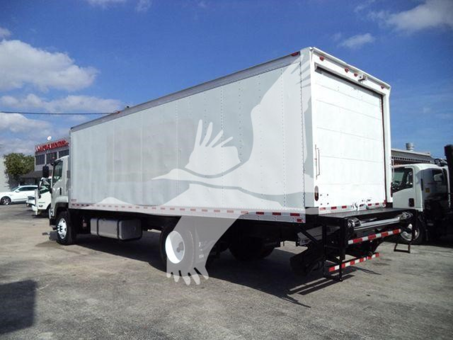 Isuzu FTR box truck in-view showing side and rear; VIN label not readable; generic truck yard background.
