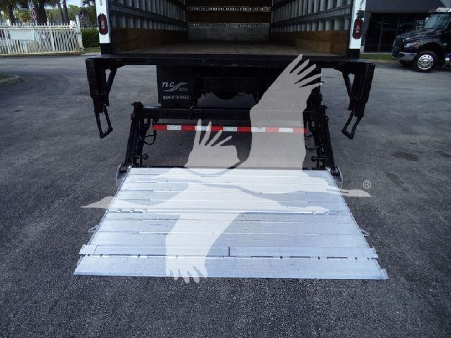 Isuzu FTR truck rear with lowered aluminum ramp, hydraulic lift, and supporting structure visible.