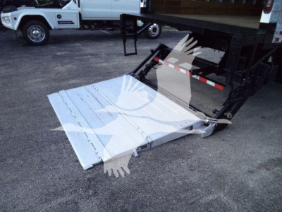 Isuzu FTR truck with a lowered flatbed ramp and lightweight metal deck showing on a truck chassis