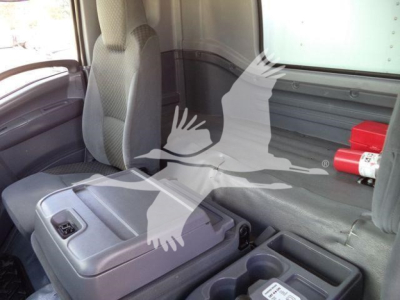 Isuzu box truck interior showing front seat area with center console and cargo area; limited view of cabin with gray upholstery.