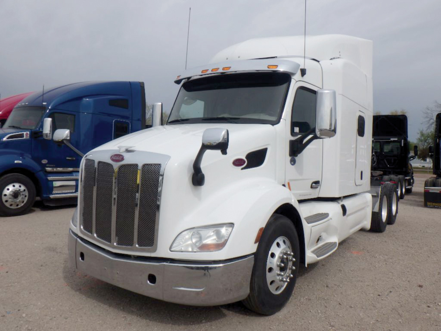Peterbilt 579 UltraCab tractor in a lot, white exterior with chrome grille and mirrors, front view showing cab and aerodynamic hood.