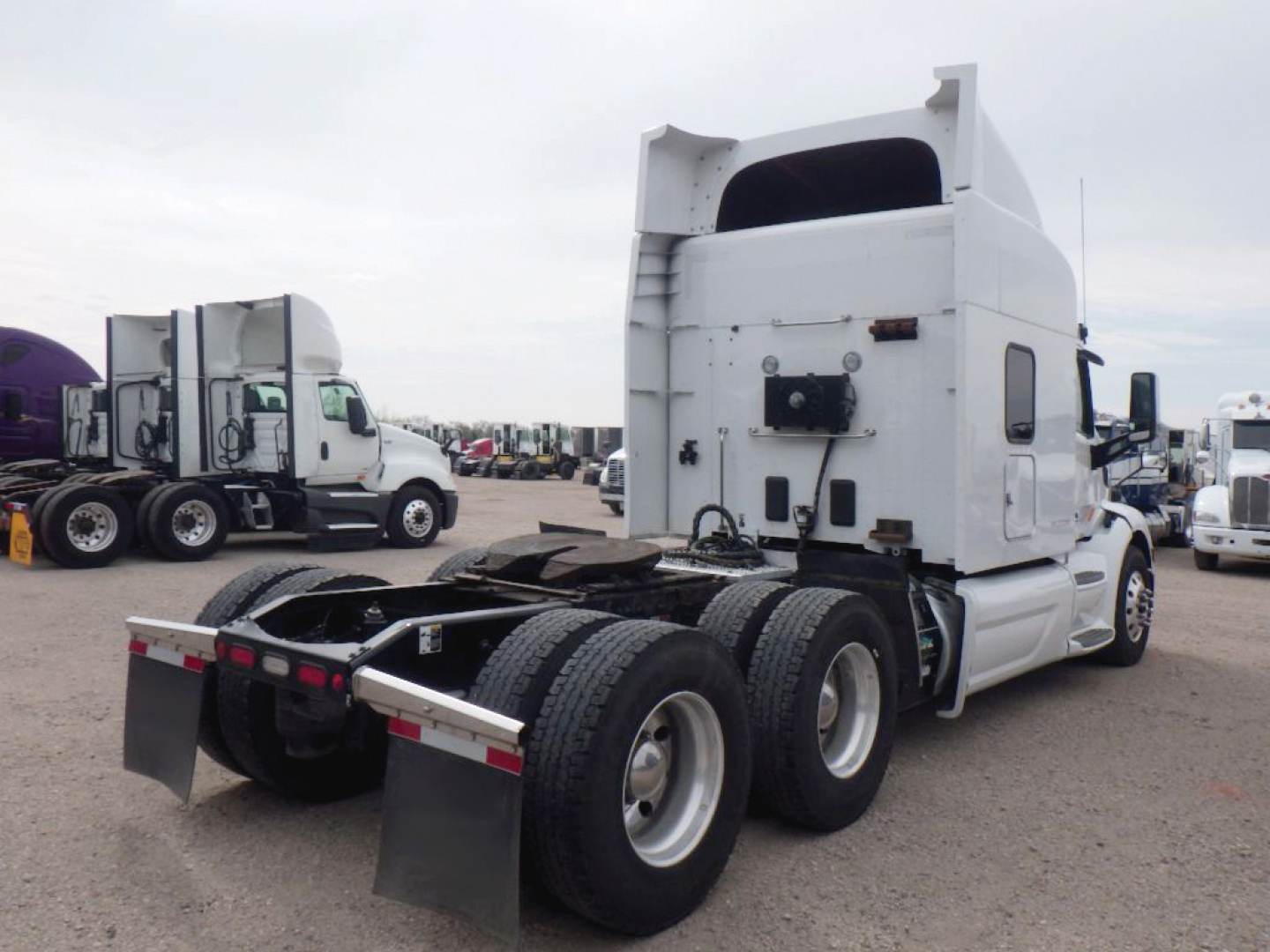 Peterbilt tractor truck 6x4 rear view showing sleeper cab and fifth wheel, chrome fuel tanks, multiple tires, and rear mudflaps.