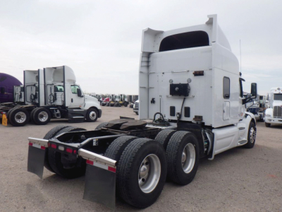 Peterbilt tractor truck 6x4 rear view showing sleeper cab and fifth wheel, chrome fuel tanks, multiple tires, and rear mudflaps.
