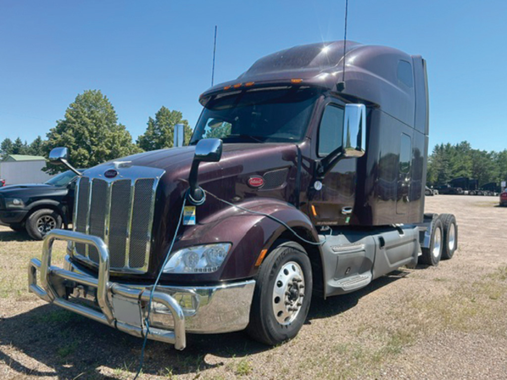 Peterbilt 579 tractor shown in a dark burgundy color with chrome bumper guard. Front grille, dual axle, high sleeper cab. No visible text on image other than reflections.