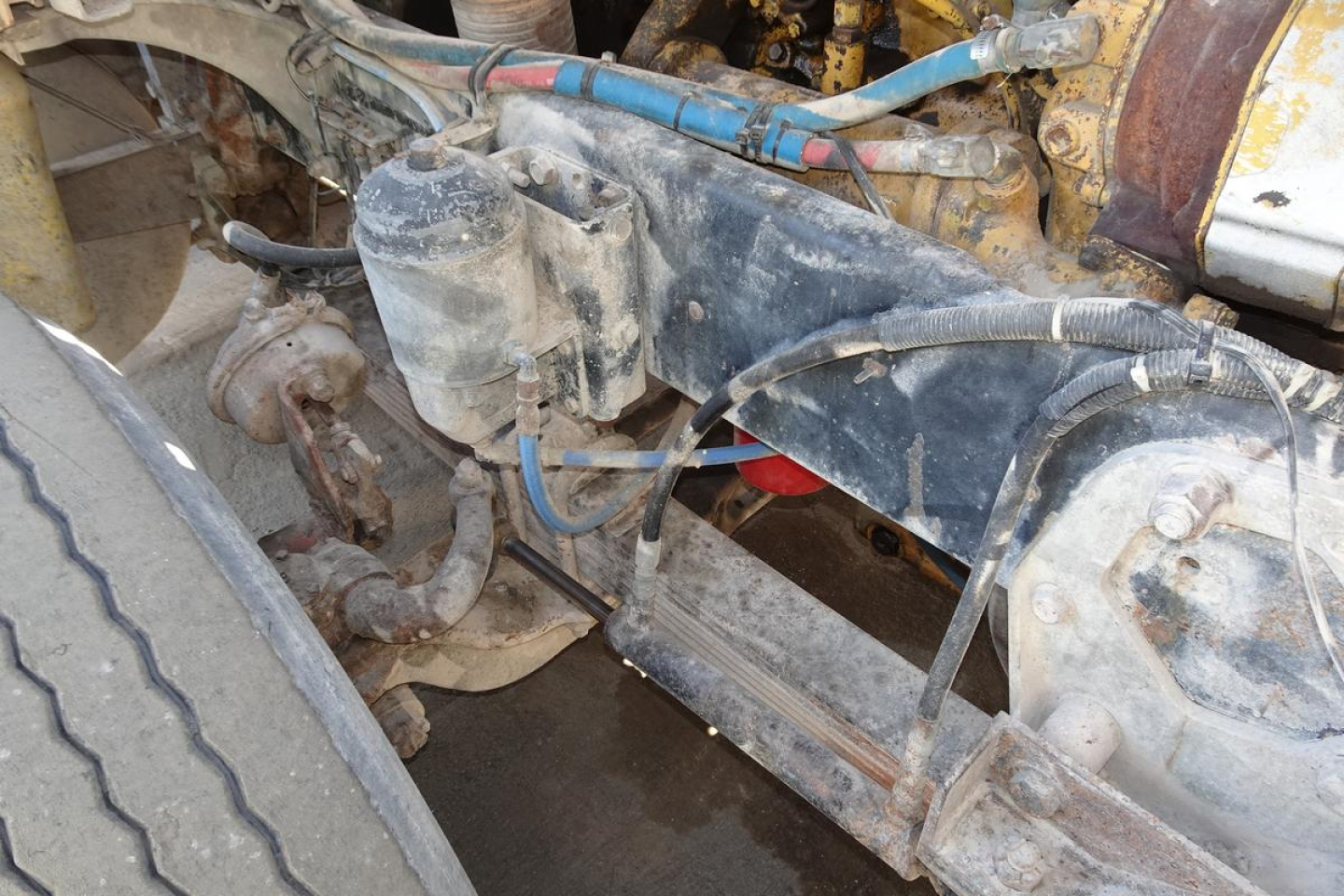 Dump truck engine bay showing hydraulic reservoir and exposed drivetrain components.
