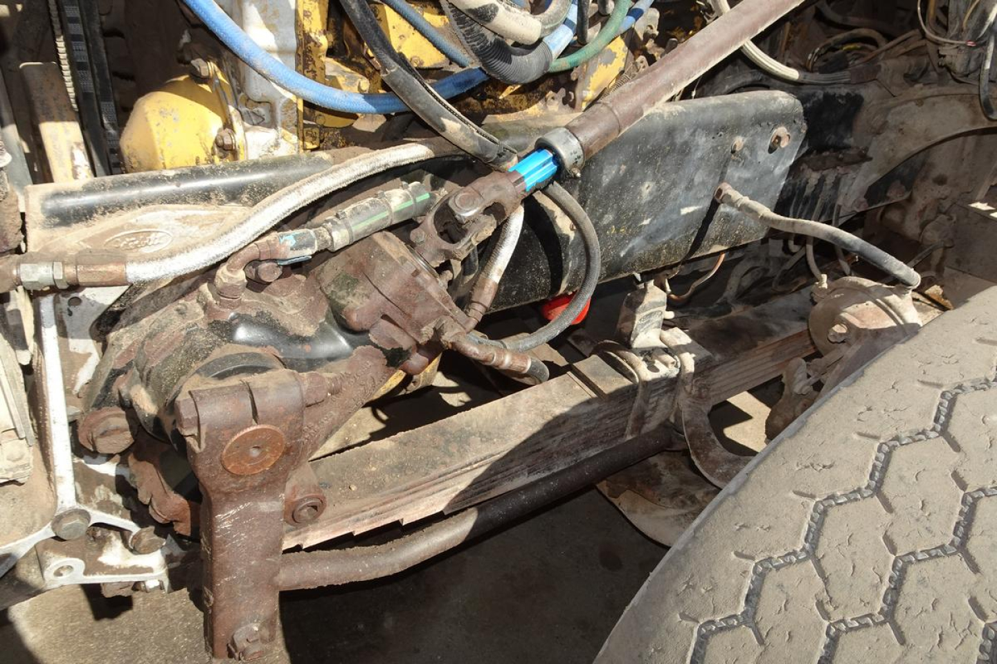 Peterbilt engine bay showing hydraulic lines, hoses, and front suspension components.