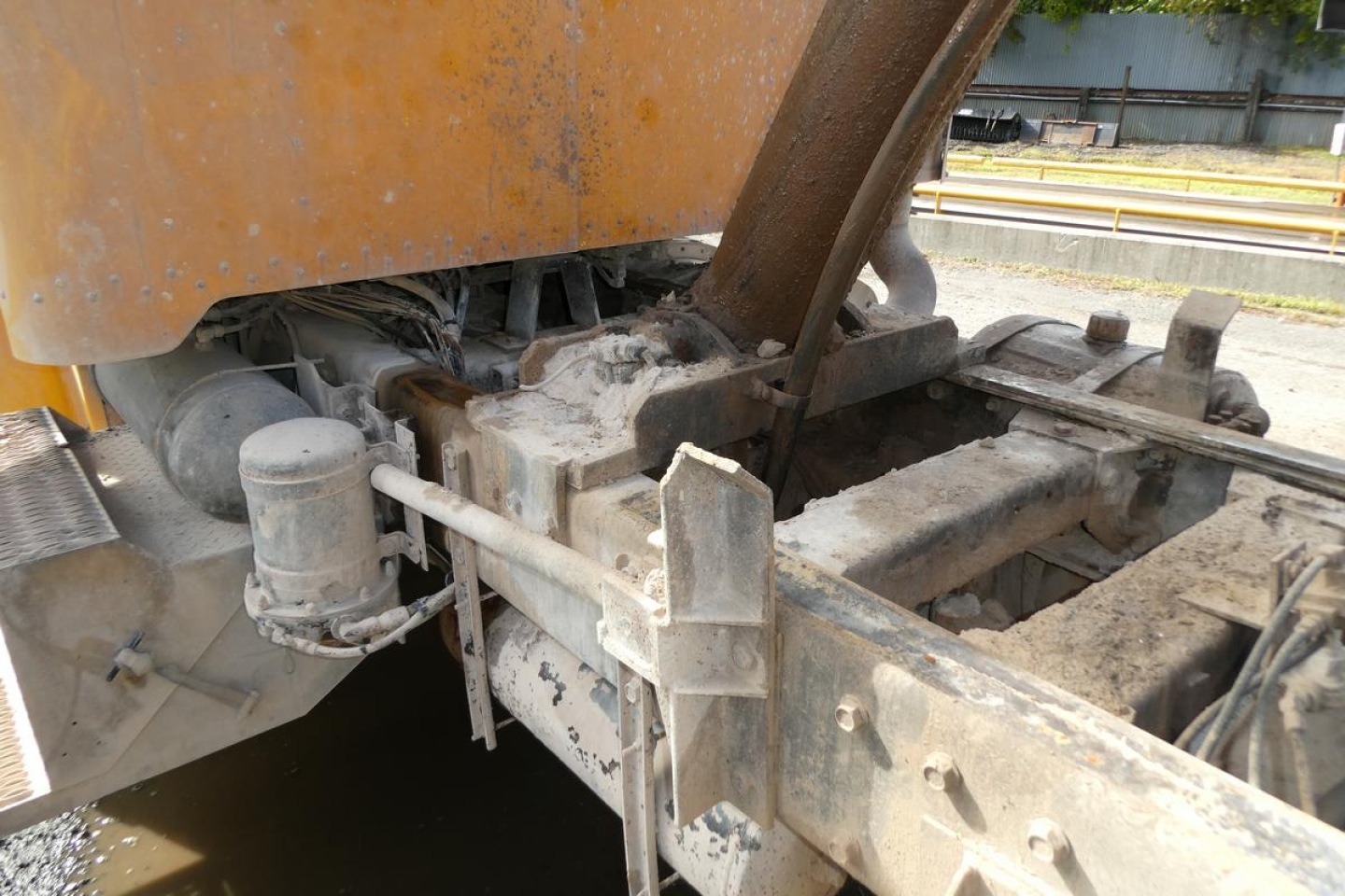 Peterbilt truck chassis area showing hydraulic reservoir, metal framework, and linkage components with orange body paint visible