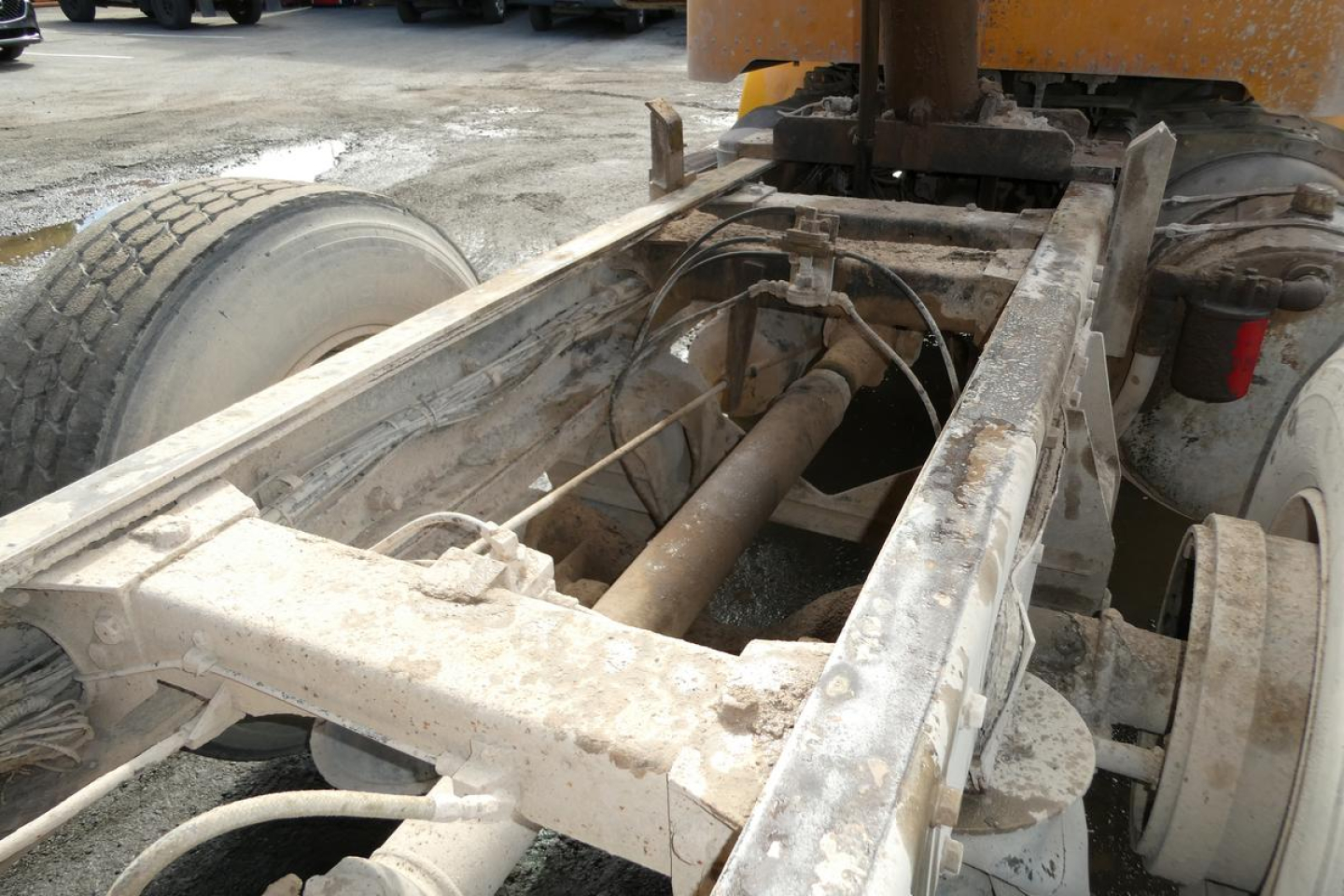 Peterbilt chassis with exposed undercarriage and drivetrain, front wheel and suspension visible, rust-resistant metal frame, hydraulic hoses and cables present.