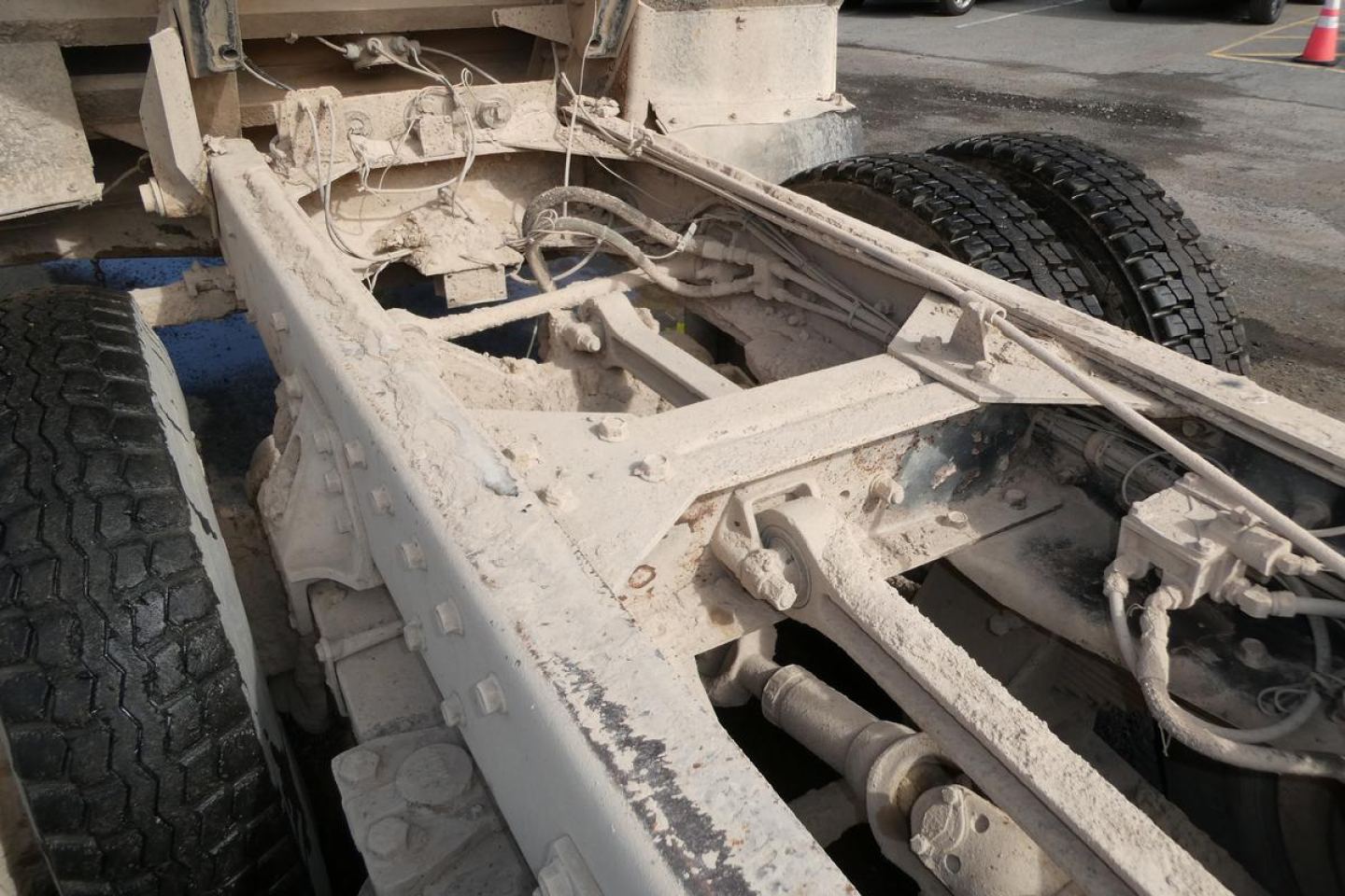 Peterbilt truck chassis frame and dual rear wheels, exposed metal framework with dirt and grime, undercarriage view.