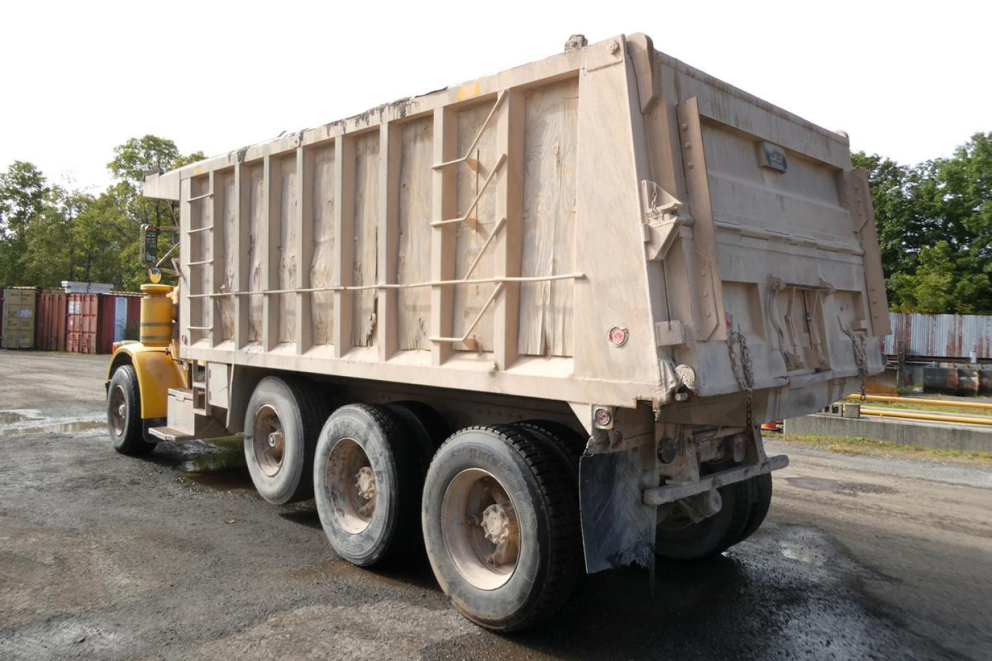 Peterbilt 357 dump truck side/rear view showing large beige dump bed and triple axle rear, VIN sticker area not readable.