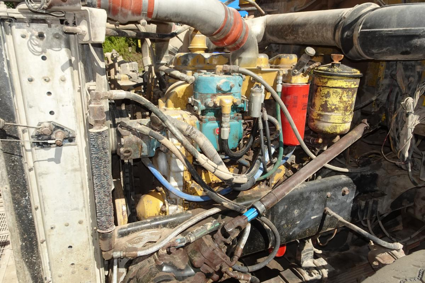 Peterbilt 357 engine bay showing coolant hoses, blue coolant reservoir, yellow filters, and red canister; various hoses and metal components.