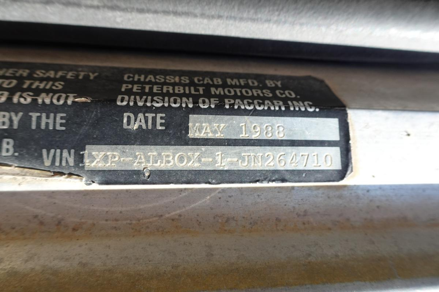 Plate showing Peterbilt Motors Co., Division of PACCAR Chassis Cab Mfg. Co. date May 1988 and VIN 1XP-ALB0X-1-JN264710.