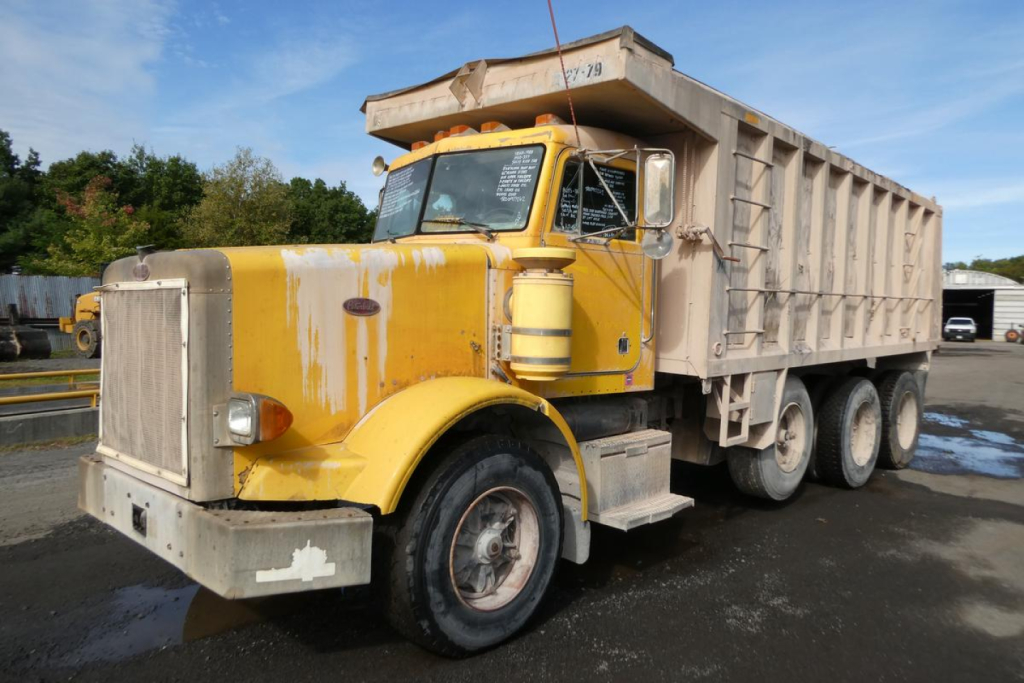 Peterbilt 357 dump truck in-service showing yellow cab and grey dump bed with visible front grille, round headlights, and dual rear axles.