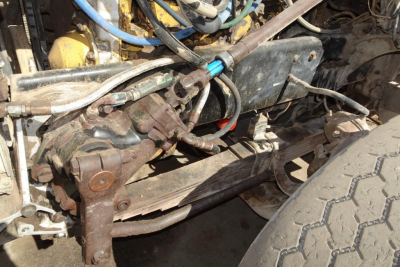 Peterbilt engine bay showing hydraulic lines, hoses, and front suspension components.